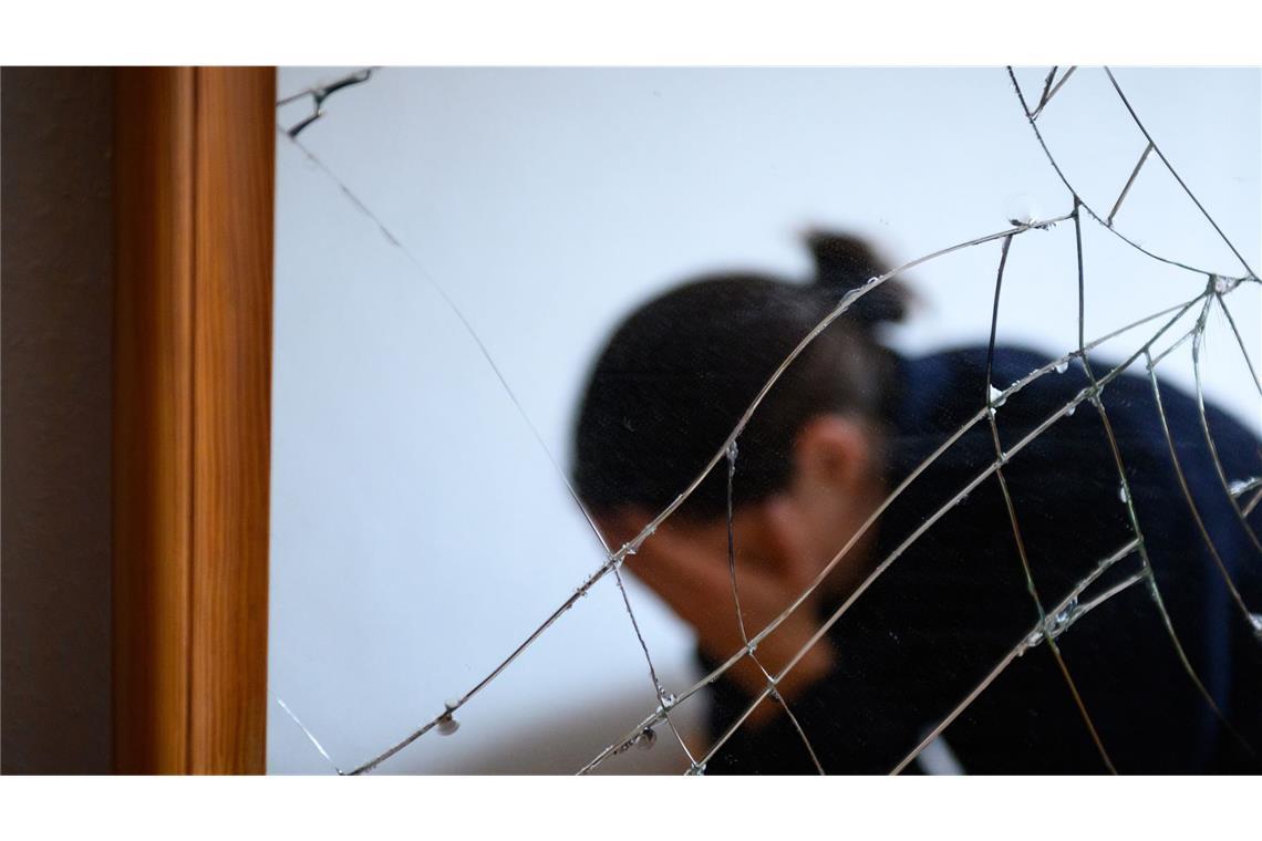 Regierung will Frauen besser vor Gewalt schützen Eine Frau sitzt neben einem gesprungenen Spiegel auf einem Bett und hält ihren Kopf in den Händen. Ein Gesetzentwurf soll Frauen besser vor Gewalt schützen (Symbolfoto).