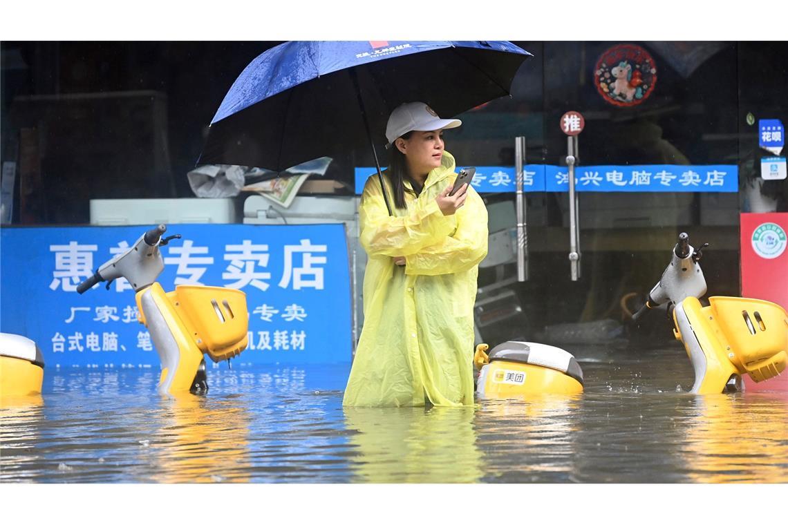 Eine Frau steht in Qinzhou auf einer mit Wasser vollgelaufenen Straße.