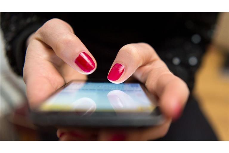 Eine Frau tippt auf einem Smartphone (Symbolbild)