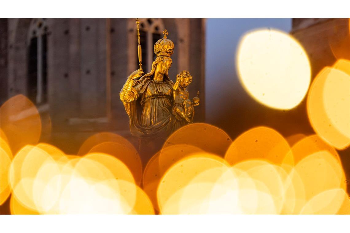 Bilder des Tages Eine goldene Marienfigur steht auf dem Marienplatz in München im Licht des umliegenden Weihnachtsmarkts.