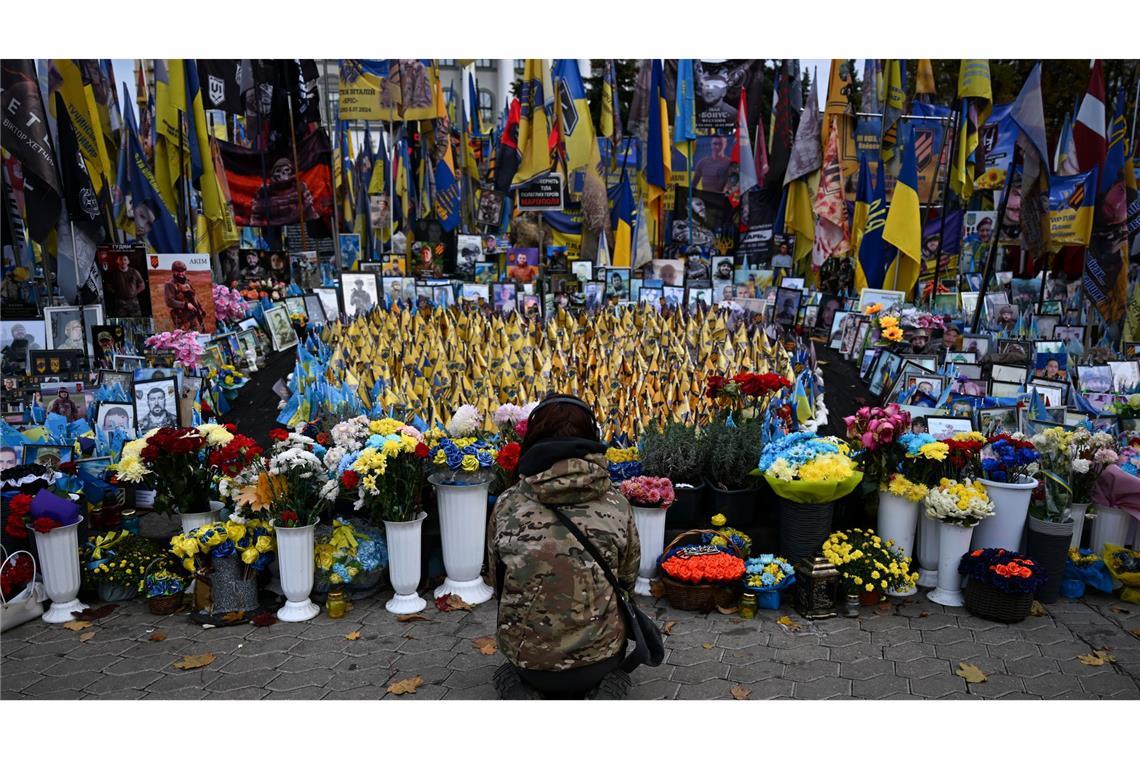 Eine junge Frau kniet am Unabhängigkeitsplatz Maidan in Kiew. Hier wird den Gefallenen des Krieges gedacht.