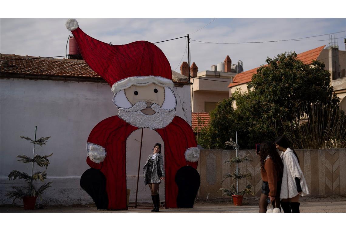Bilder des Tages Eine junge Frau posiert für ein Foto an einer Weihnachtsdekoration auf einem Platz in einem christlichen Viertel in der syrischen Stadt Homs.