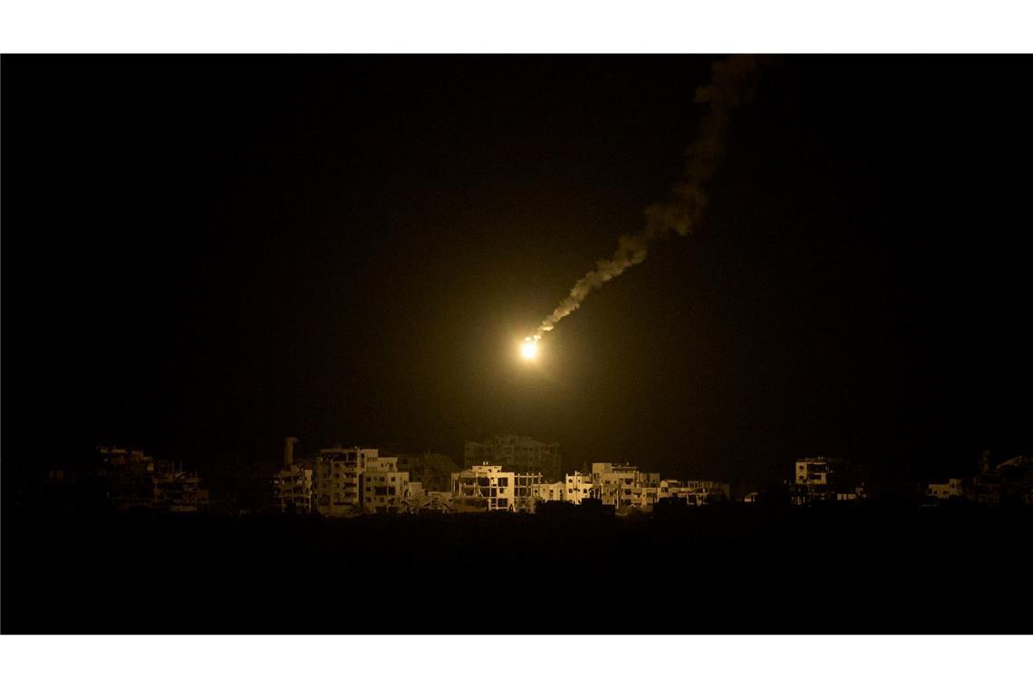 Eine Leuchtrakete der israelischen Armee fliegt über Gebäuden, die während der israelischen Boden- und Luftoperationen im nördlichen Gazastreifen zerstört wurden.