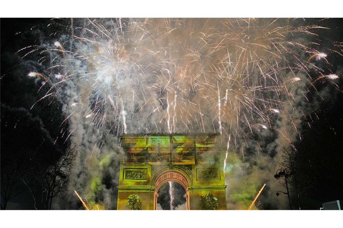 Eine Lichtshow wird auf den Arc de Triomphe projiziert, während ein Feuerwerk im Rahmen der Neujahrsfeierlichkeiten auf den Champs Elysees gezündet wird.