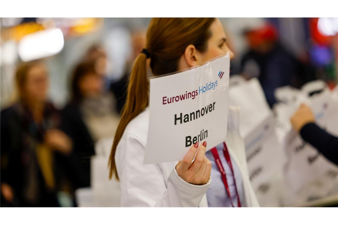 Eine Mitarbeiterin der Fluggesellschaft Eurowings hält ein Schild.