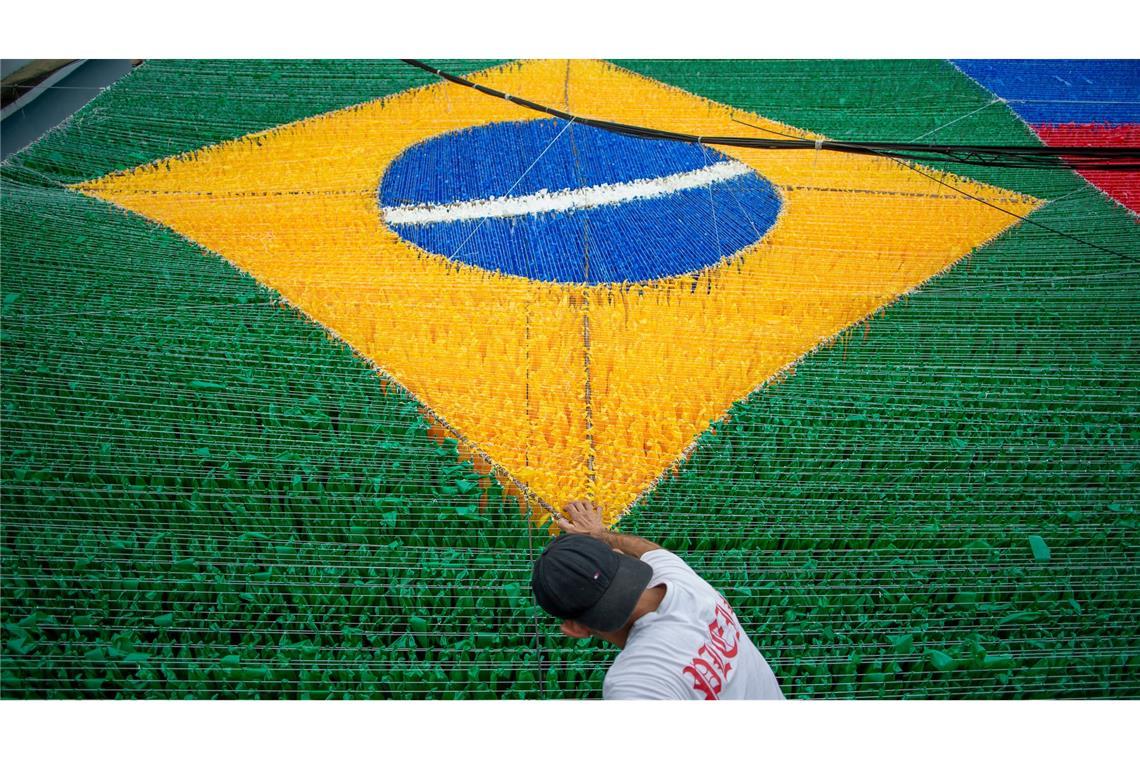 Eine Person gibt der hängenden Dekoration zur Feier der Fußballweltmeisterschaft 2026 auf der Rua 03 im Viertel Alvorada in Manaus, der Hauptstadt des brasilianischen Bundesstaates Amazonas, den letzten Schliff.