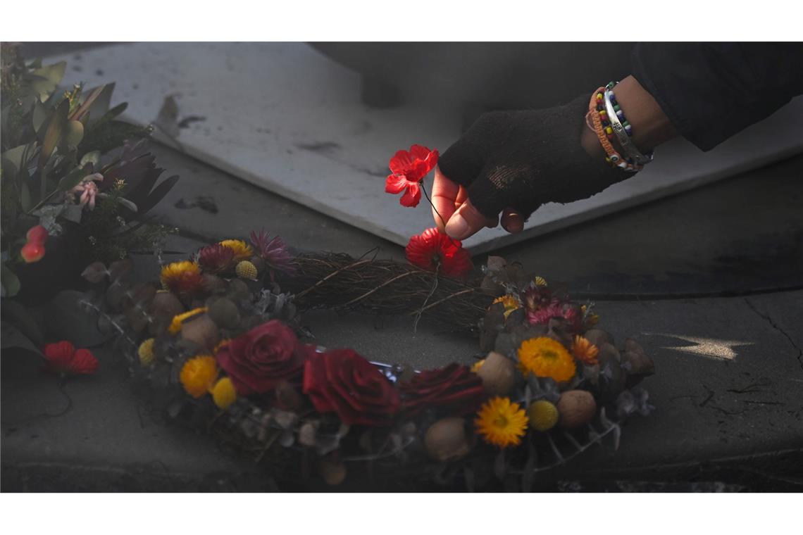 Eine Person legt eine Mohnblume an der Gedenkstätte "Für unser Land" während der Gedenkfeier für Aborigines und Torres-Strait-Insulaner (ATSIVA) im Rahmen des Anzac-Tags am Australian War Memorial in Canberra nieder.