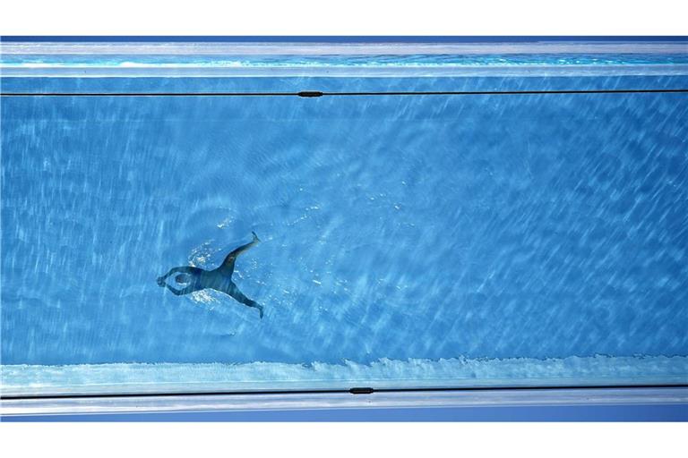 Eine Person schwimmt im Sky Pool, einem transparenten Schwimmbecken, das 35 Meter über dem Boden zwischen zwei Wohngebäuden in London aufgehängt ist,