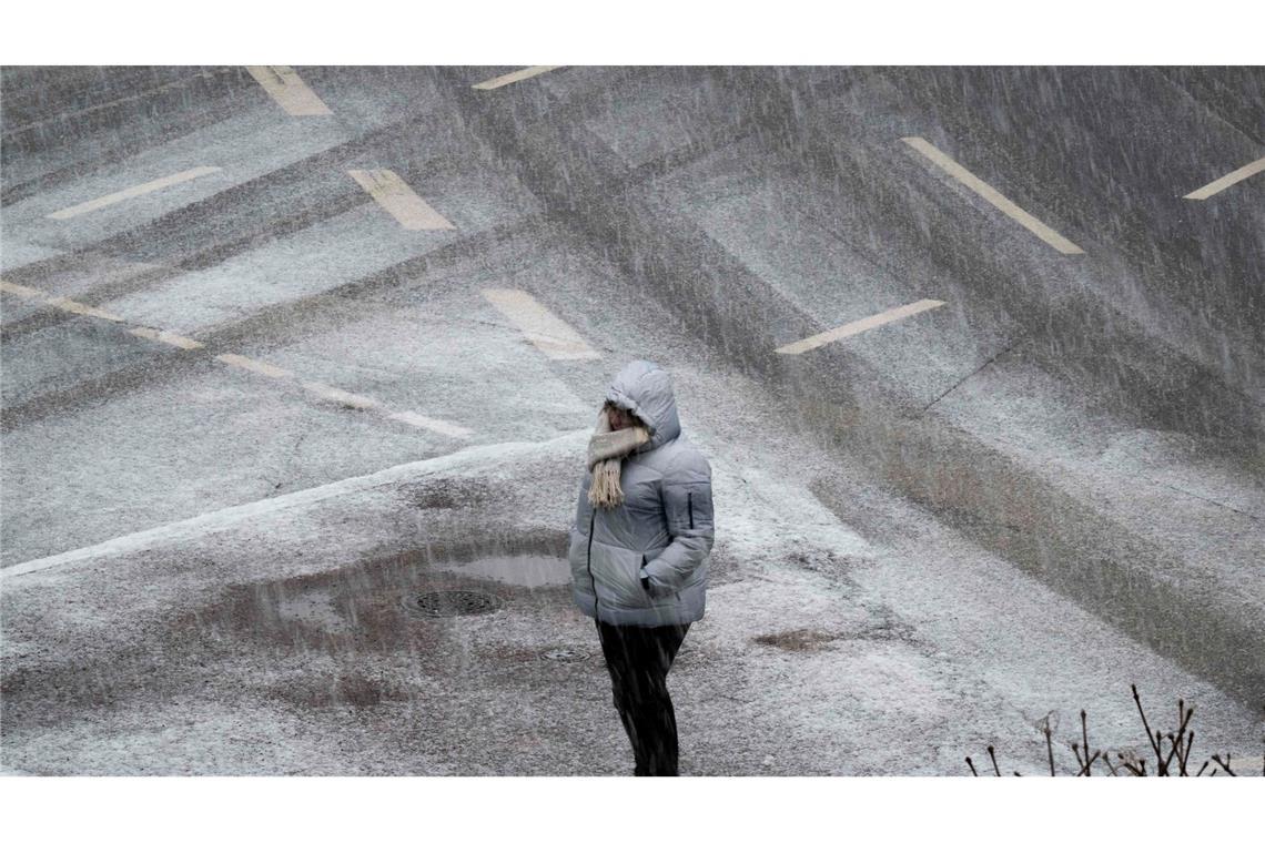 Eine Person steht bei starkem Schneefall an einer Kreuzung in Frankfurt.
