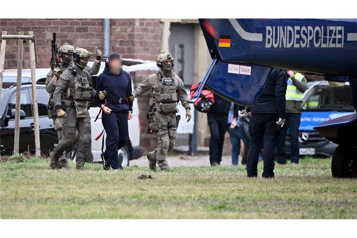 Eine Person wird von Polizeibeamten zu einem Hubschrauber gebracht.
