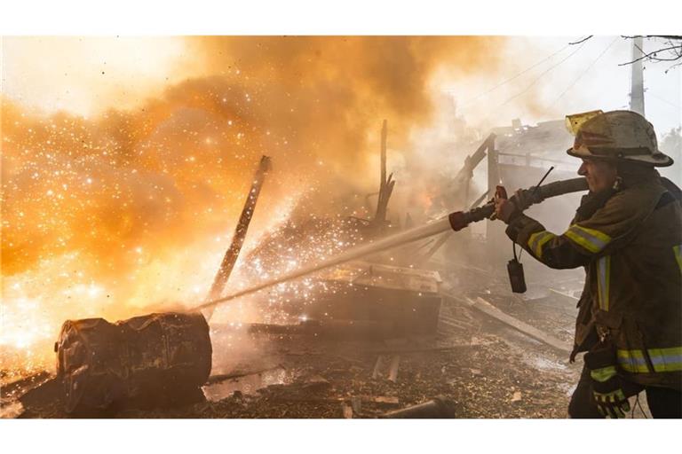 Eine Rettungskraft löscht einen Brand in Wohnhäusern, die bei einem russischen Angriff zerstört wurden.