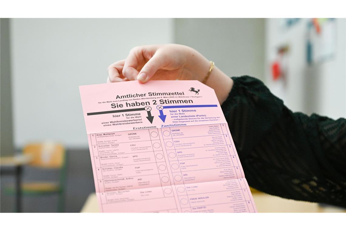 Eine Wahlhelferin in einem Stuttgarter Wahllokal zeigt den Stimmzettel.