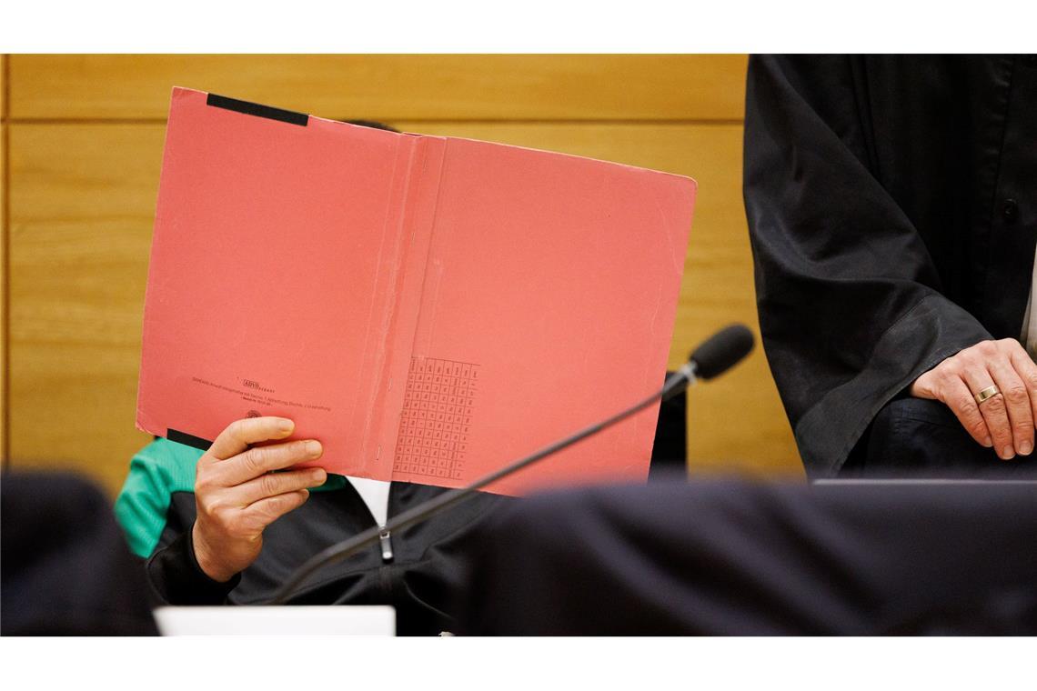 Einer der Angeklagten am Landgericht Bielefeld sitzt neben seinem Verteidiger und verdeckt sein Gesicht.