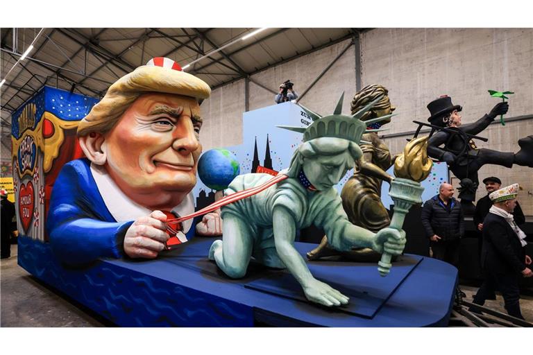 Einer der Wagen im Kölner Rosenmontagszug zeigt US-Präsident Donald Trump, der die Freiheitsstatue und die Justitia am Laufband führt.