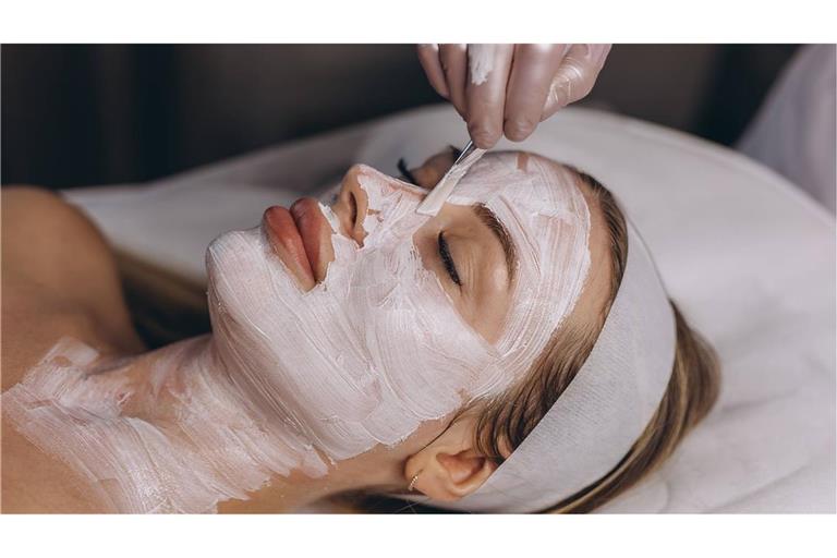 Einer Frau wird in einem Kosmetikstudio eine Gesichtsmake aufgetragen.