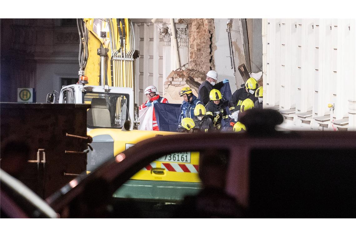 Einsatzkräfte der Feuerwehr tragen hinter Sichtschutz eine Leiche aus dem Trümmerfeld eines eingestürzten Hauses in Görlitz.