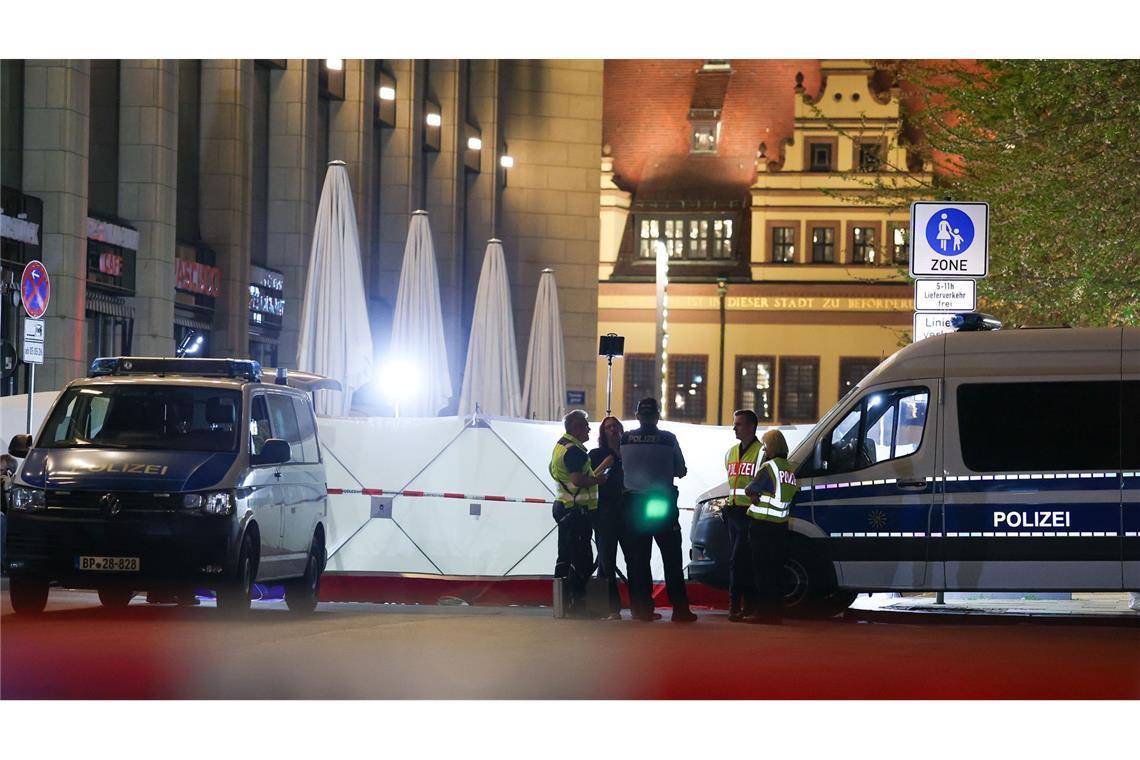 Einsatzkräfte stehen neben dem Sichtschutz vor dem Tatfahrzeug in der Grimmaischen Straße. In Leipzig ist ein Auto in mehrere Menschen gefahren.