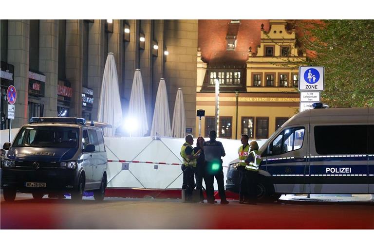 Einsatzkräfte stehen neben dem Sichtschutz vor dem Tatfahrzeug in der Grimmaischen Straße. In Leipzig ist ein Auto in mehrere Menschen gefahren.