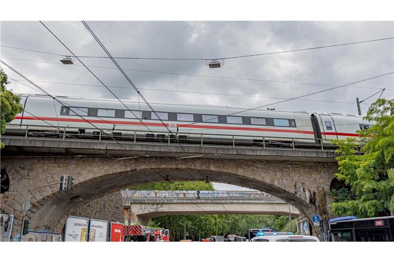 Einsatzkräfte von Polizei und Feuerwehr stehen an einer Eisenbahnunterführung am Bergischen Ring, auf der ein ICE liegengeblieben ist.