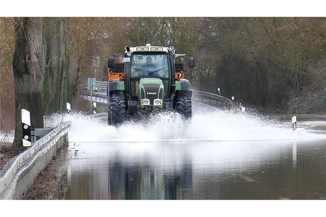 Ein Traktor fährt über die überschwemmte Lahnparkstraße in Heuchelheim.