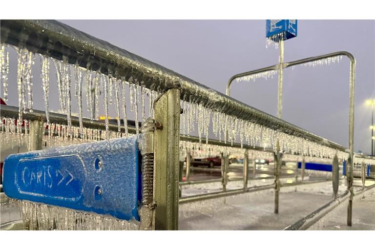 Eiszapfen hängen an einem Geländer während eines Wintersturms auf einem Parkplatz.