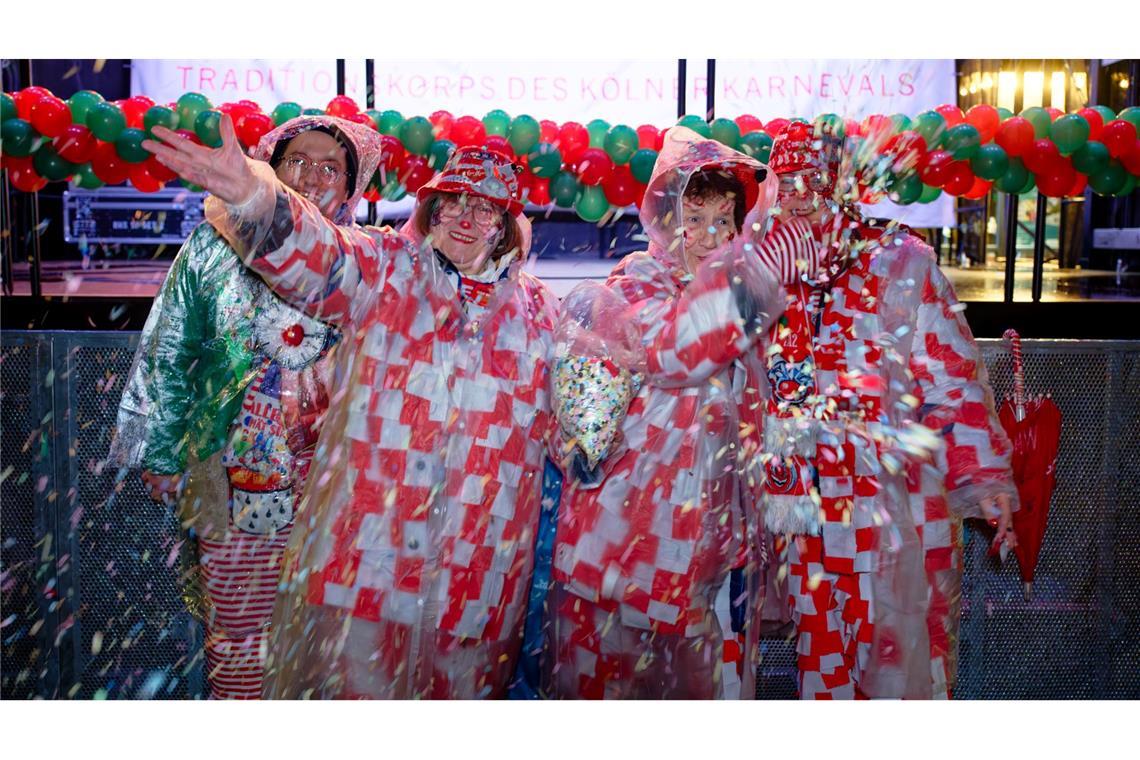 Erste Jecken warten im Regen auf dem Alter Markt an Weiberfastnacht auf den Beginn des Straßenkarnevals in Köln.