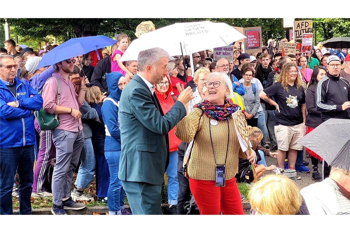 Es regnet kurzzeitig. Eine Frau reicht Palmer einen Schirm.