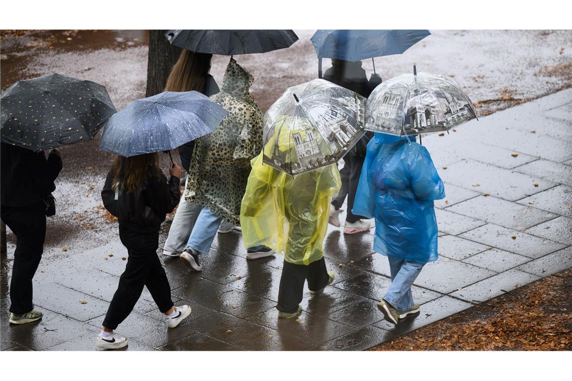 Es wird Regen geben! Jugendliche halten Schirme bei Regenwetter in Dresden.