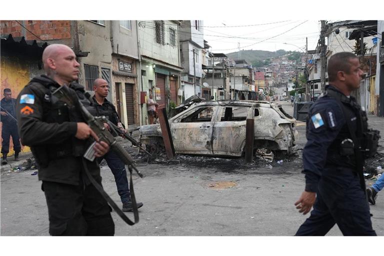 Favela „Complexo Alemao“: Polizisten gehen am Tag danach an einem verbrannten Auto vorbei.