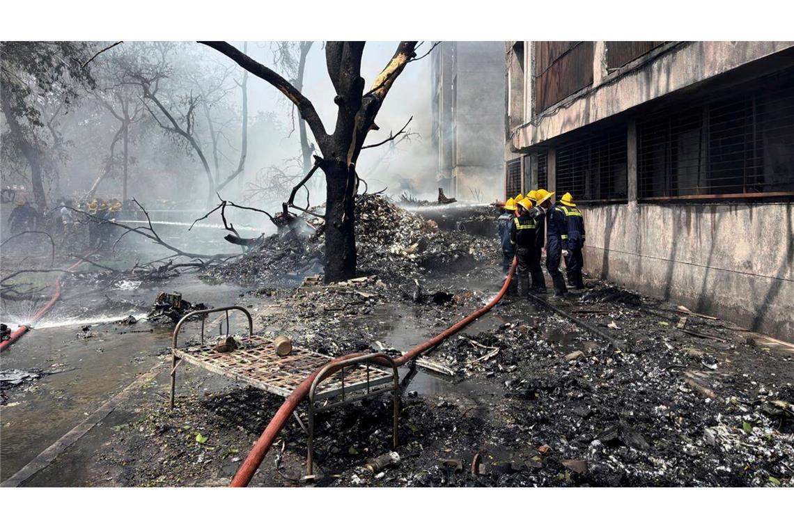 Flugzeugabsturz in Indien: Was wir wissen - und was nicht Feuerwehrleute arbeiten an der Absturzstelle.