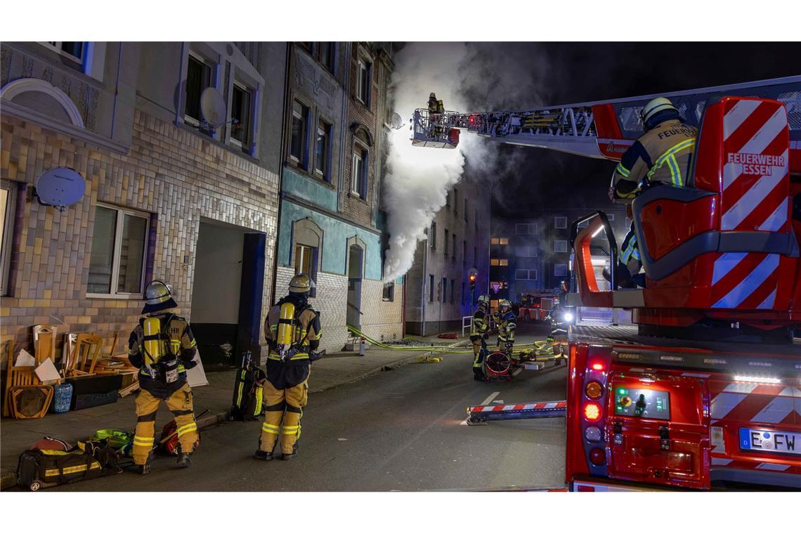 Feuerwehrleute sind u.a. mit einer Drehleiter damit beschäftigt, einen Brand in einem Wohnhaus in Essen zu bekämpfen.