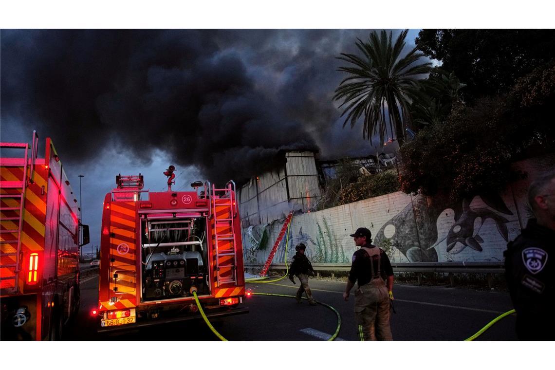 Feuerwehrleute versuchen in Holon in Israel nach einem iranischen Raketeneinschlag ein Feuer zu löschen.