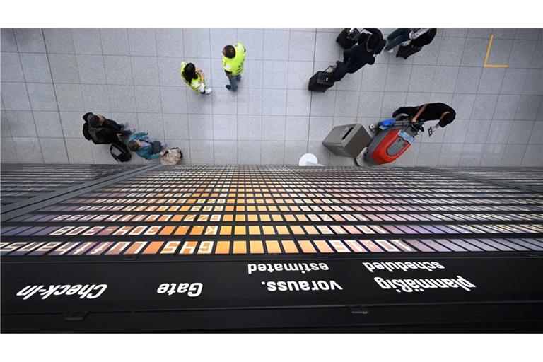 Fluggäste stehen unter einer Anzeigentafel im Terminal 2. Der Flughafen München erwartet zu Beginn der Pfingstferien Hunderttausende Fluggäste.