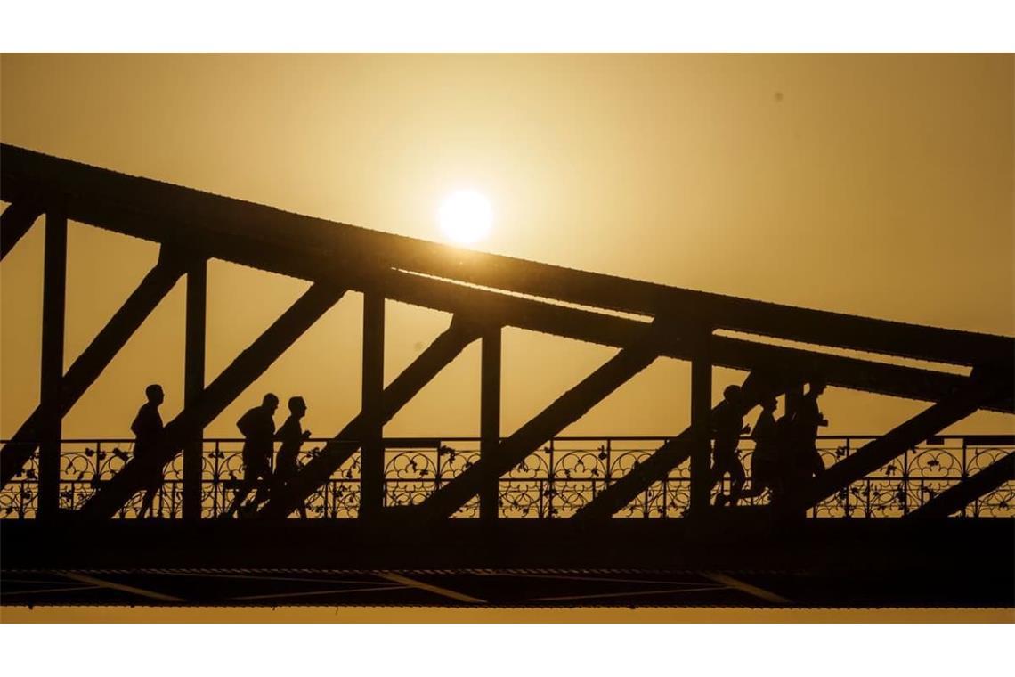 Frankfurt am Main: Eine Gruppe joggt bei Sonnenaufgang über den Eisernen Steg. 