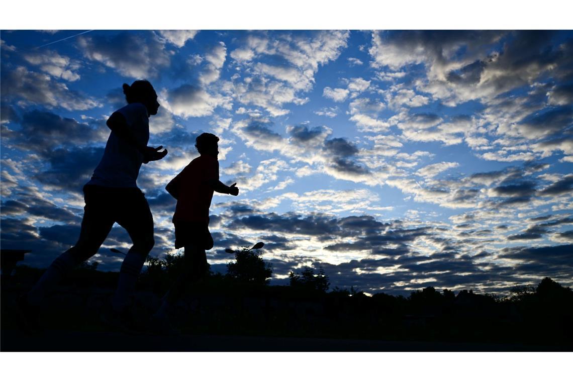 Bilder des Tages Frühsport in der Hauptstadt: Zwei Jogger laufen am Morgen in Berlin unter einem bewölkten Himmel.
