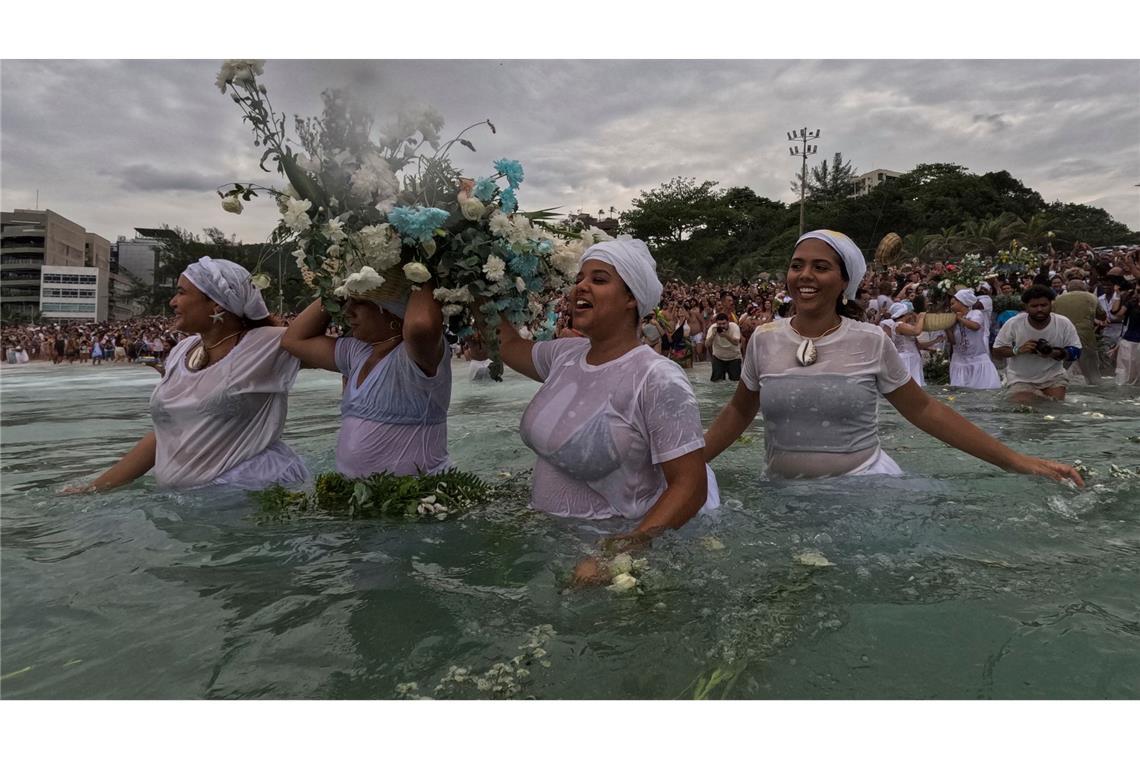 Gläubige werfen Blumen in das Wasser.