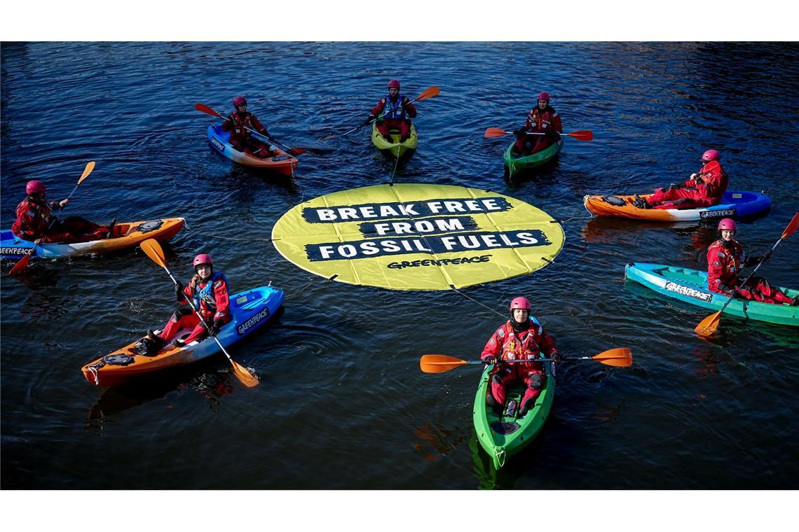 Greenpeace fordert bei einer Aktion am Veranstaltungsort die Abkehr von fossilen Energien.