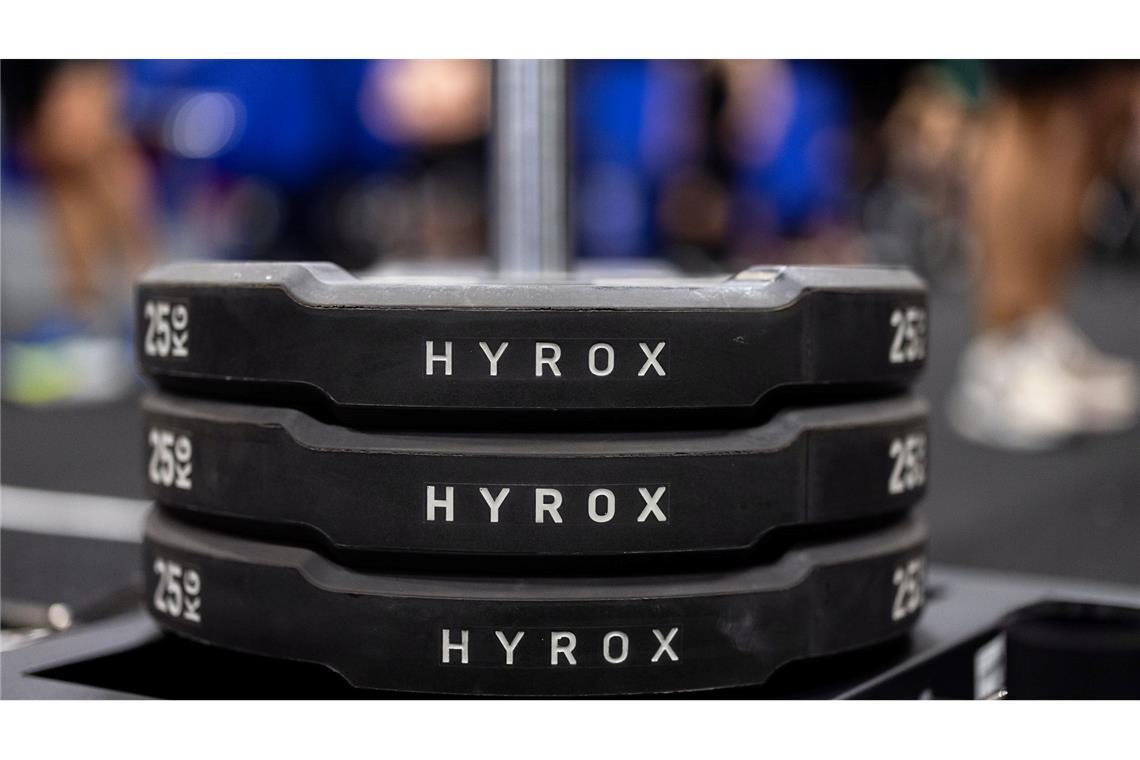 Hantelscheiben mit dem Schriftzug Hyrox an einem Messestand, wo wenig später ein Lauf- und Workout-Wettbewerb stattfinden sollte.