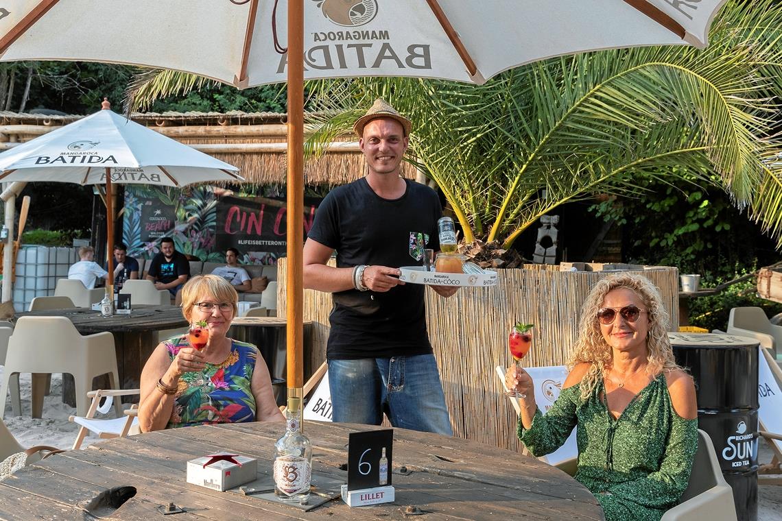 Helga und Sylvia Wörner (von links) sind aus Korb gekommen, um den Abend am „Cocoloco Beach“ zu genießen. Mike Isert serviert ihnen einen Aperitif.