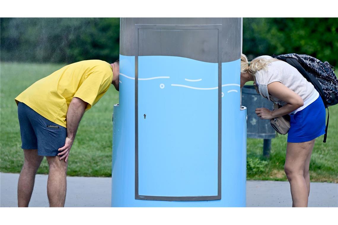 Bilder des Tages Hitze in Österreich: Zwei Personen trinken an einem Trinkbrunnen in Wien.