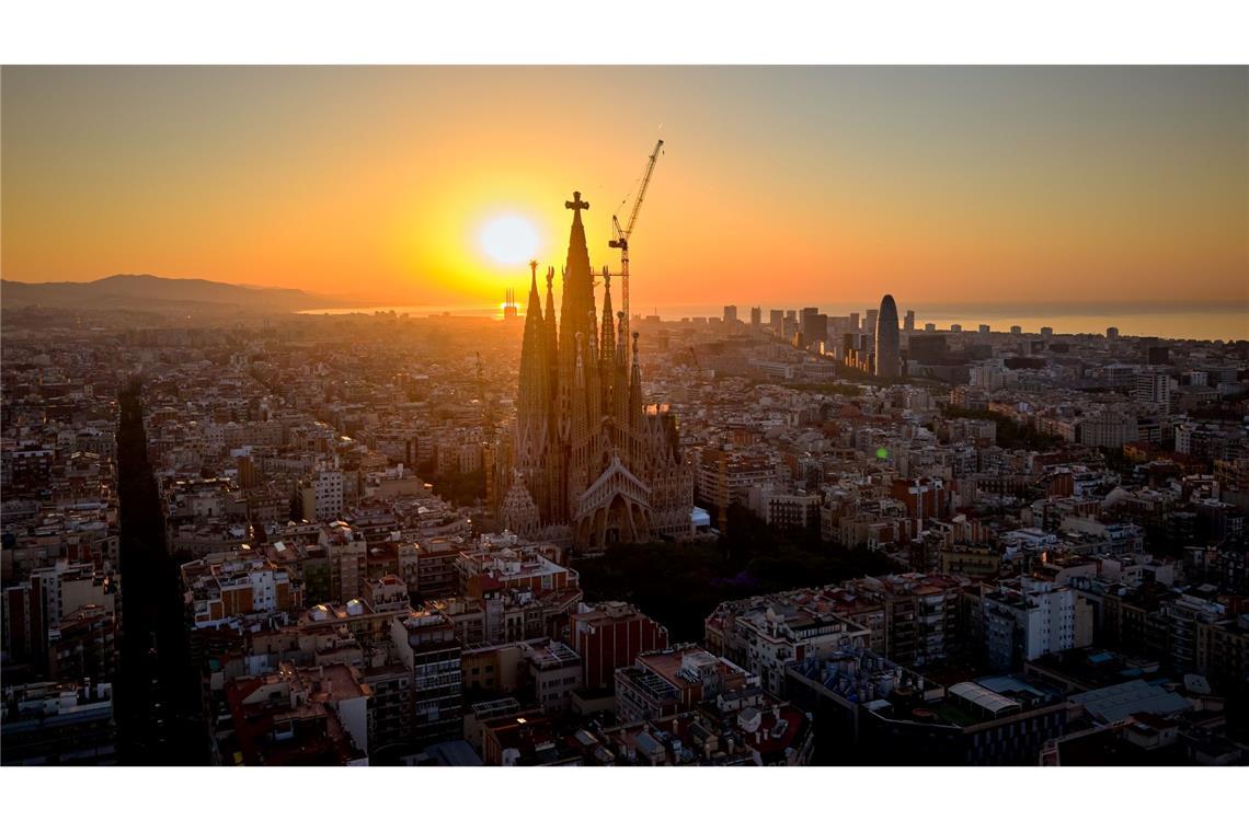 Im Gegenlicht der aufgehenden Sonne ist das Kreuz aus Deutschland auf der Spitze des höchsten Turms der Basilika Sagrada Família in Barcelona gut zu erkennen. (Archivbild)