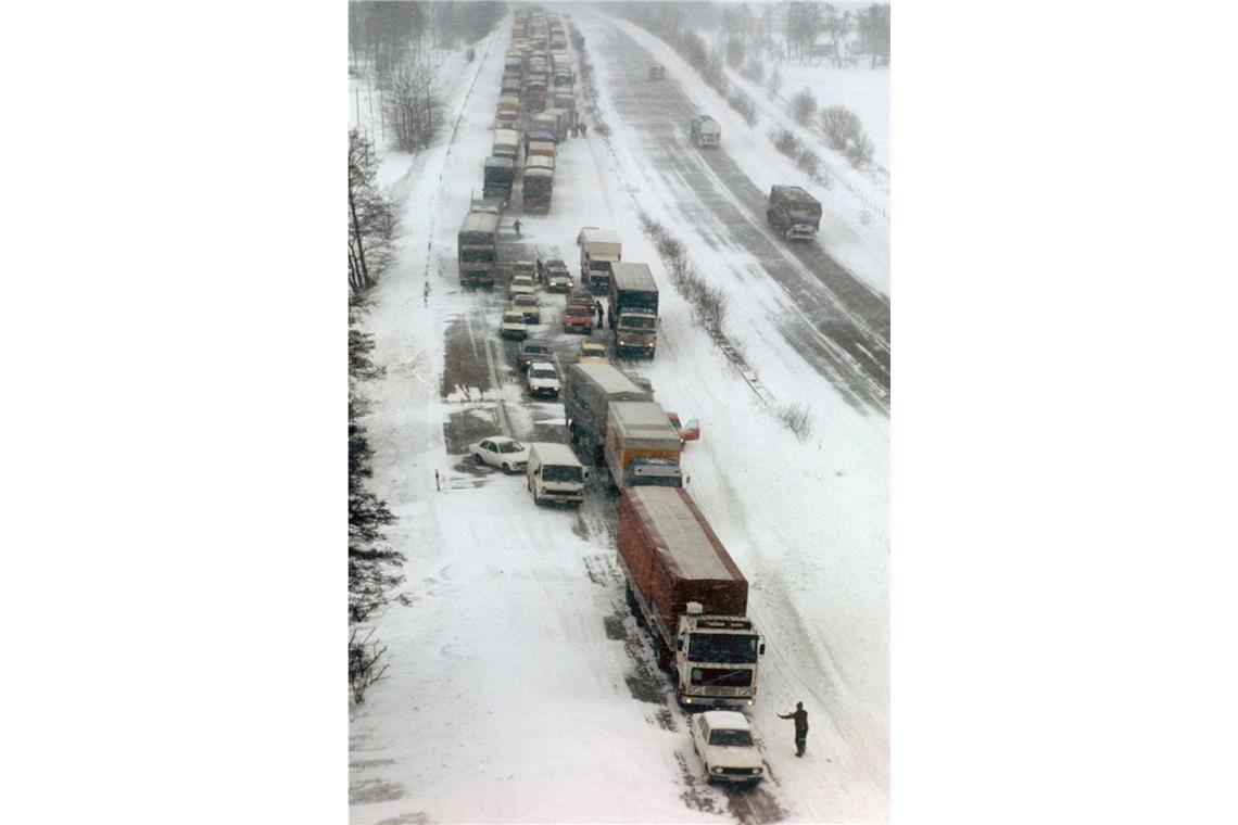 Im Schnee stecken gebliebene Lastwagen und PKW am Straßenrand der Autobahn bei Kiel.