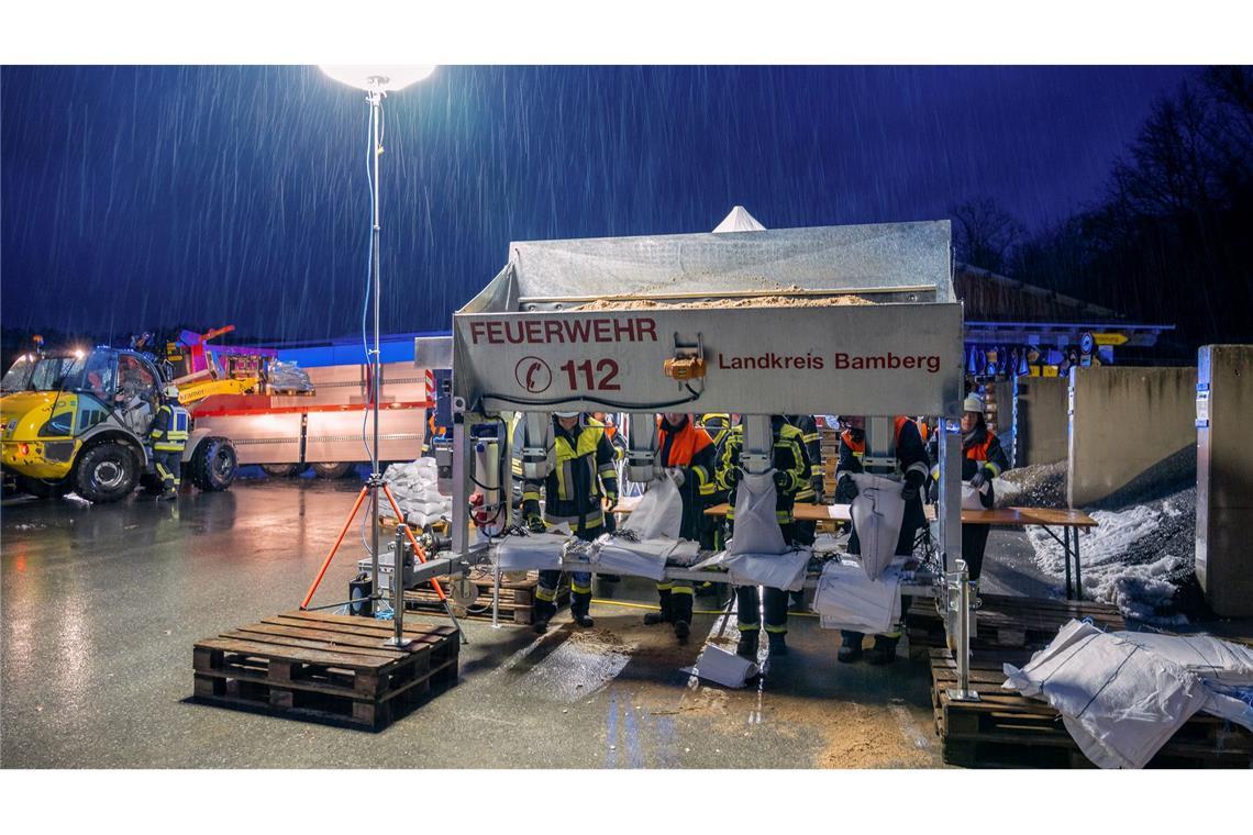 In Schlüsselfeld im Landkreis Bamberg befüllen Feuerwehrleute Sandsäcke.