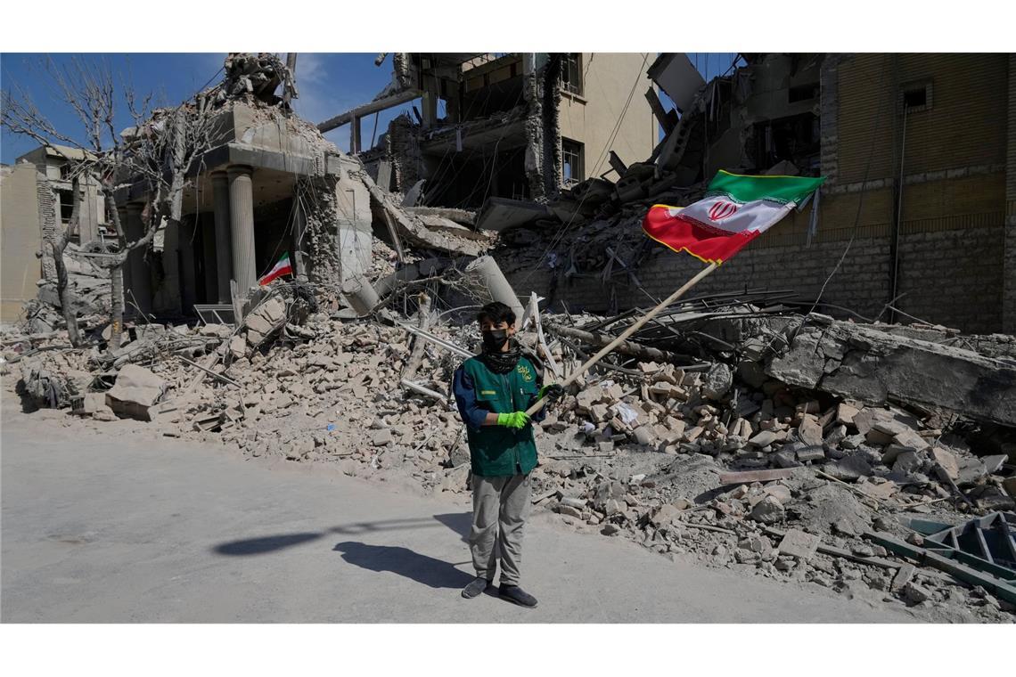 Iran-Krieg - Teheran: Ein Junge schwenkt eine iranische Flagge vor einer Polizeieinrichtung, die während der amerikanisch-israelischen Militäraktion getroffen wurde.