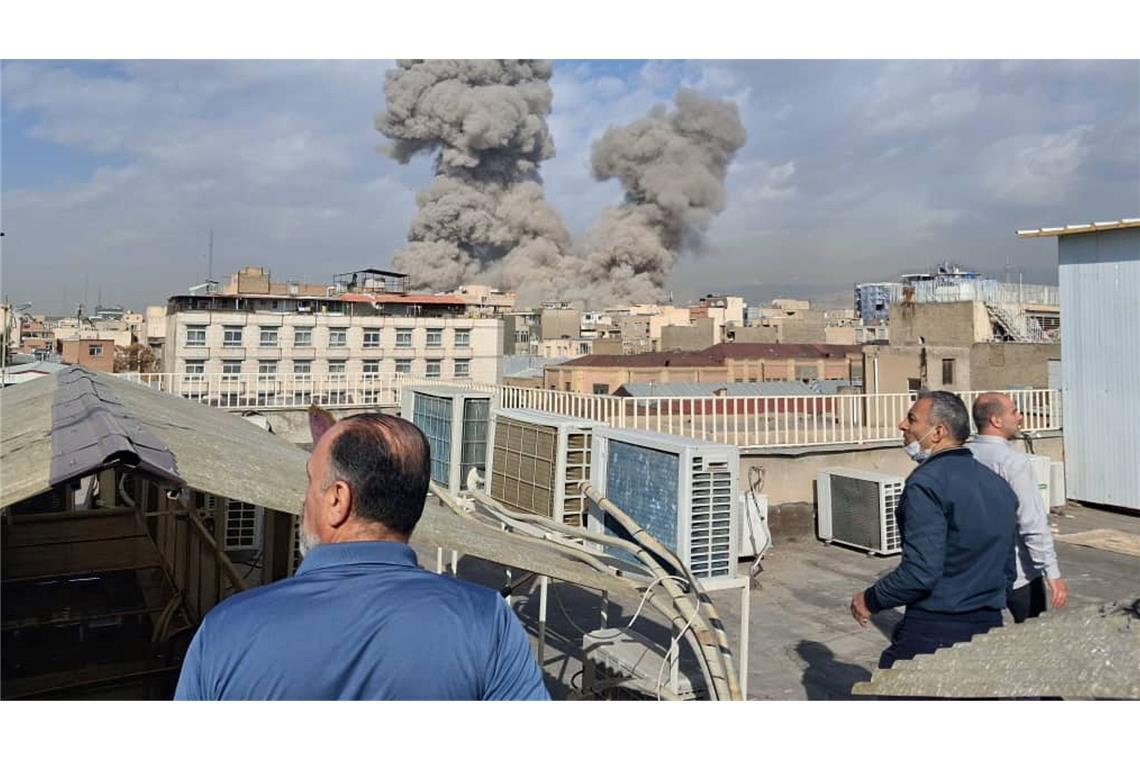 Israel greift den Iran an - Menschen beobachten Rauch nach einer Explosion in Teheran.