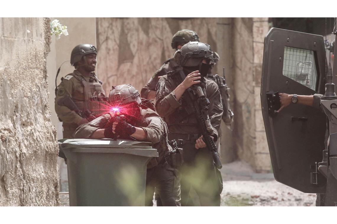 Bilder des Tages Israelische Soldaten gehen während einer Militäroperation im Norden des besetzten Westjordanlandes in Stellung. Ein Soldat zielt auf den Fotografen, man sieht die Laserzieleinrichtung leuchten. Die israelische Armee hat während einer Militäroperation in der Stadt Tamun ein Gebäude umstellt und fünf Palästinenser getötet, die sich darin verbarrikadiert hatten.