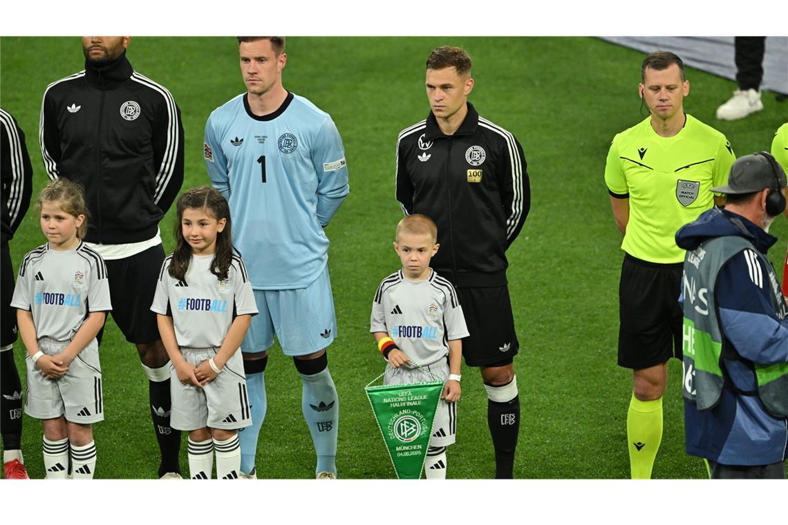 Joshua Kimmich läuft mit einem seiner Kinder auf den Rasen