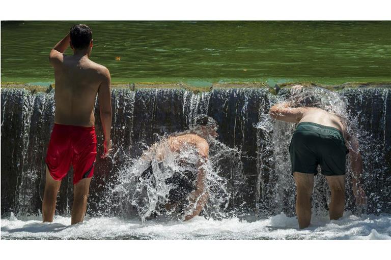 Jugendliche kühlen sich im Eisbach im Englischen Garten ab.