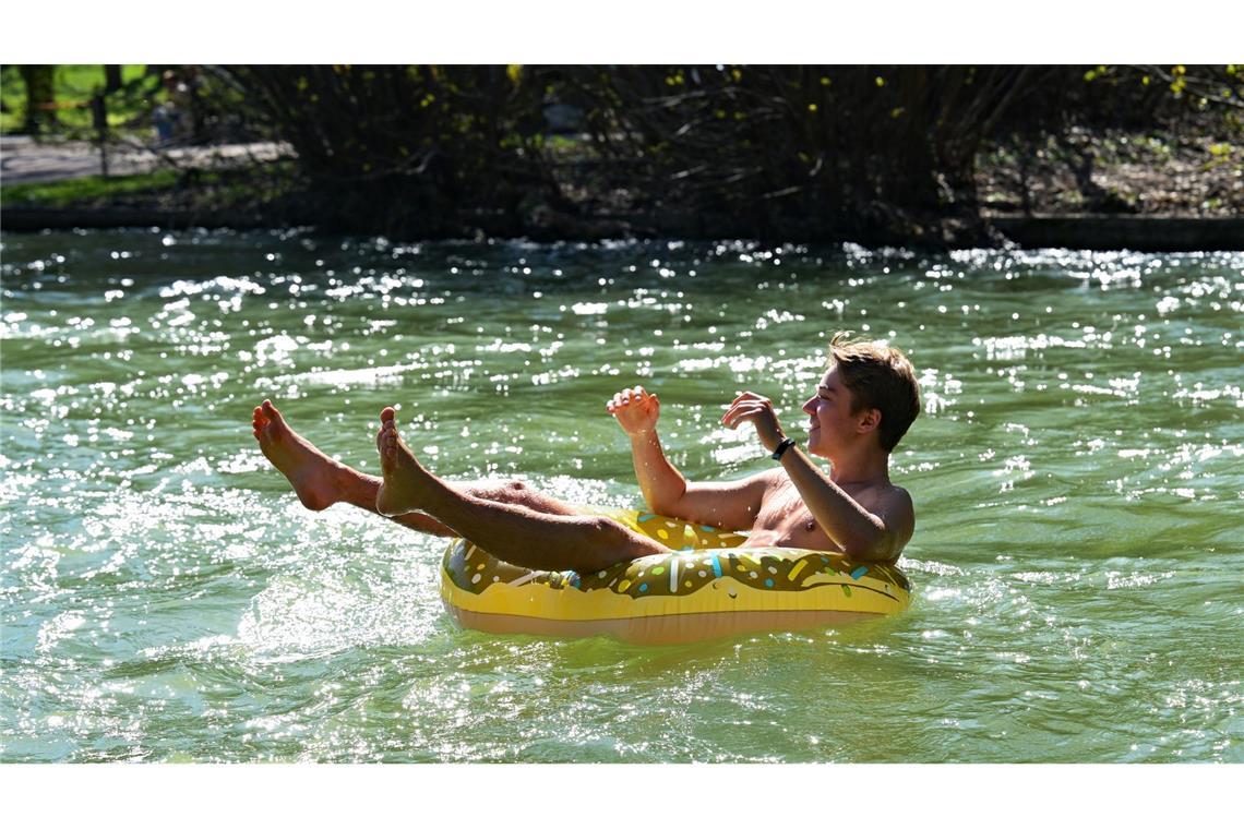 Julian treibt in einem aufblasbaren Donut im Eisbach im Englischen Garten in München.