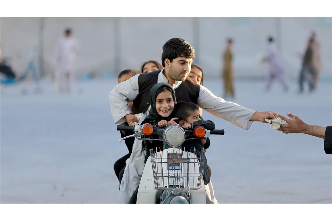 Kandahar, Afghanistan, 2013: Ein Vater bezahlt Eintritt für einen Vergnügungspark.